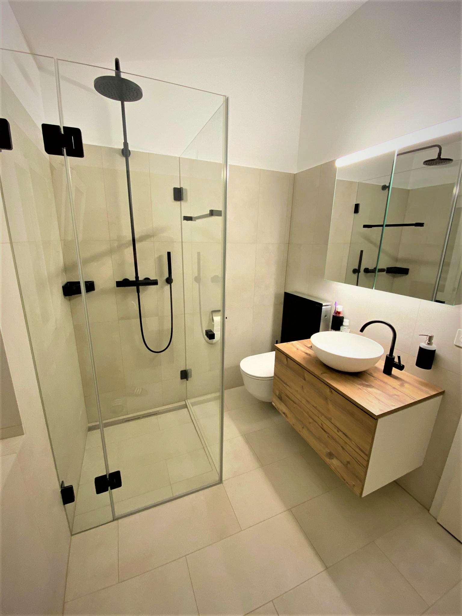 Badezimmer mit Glasdusche und Holz-Waschtisch