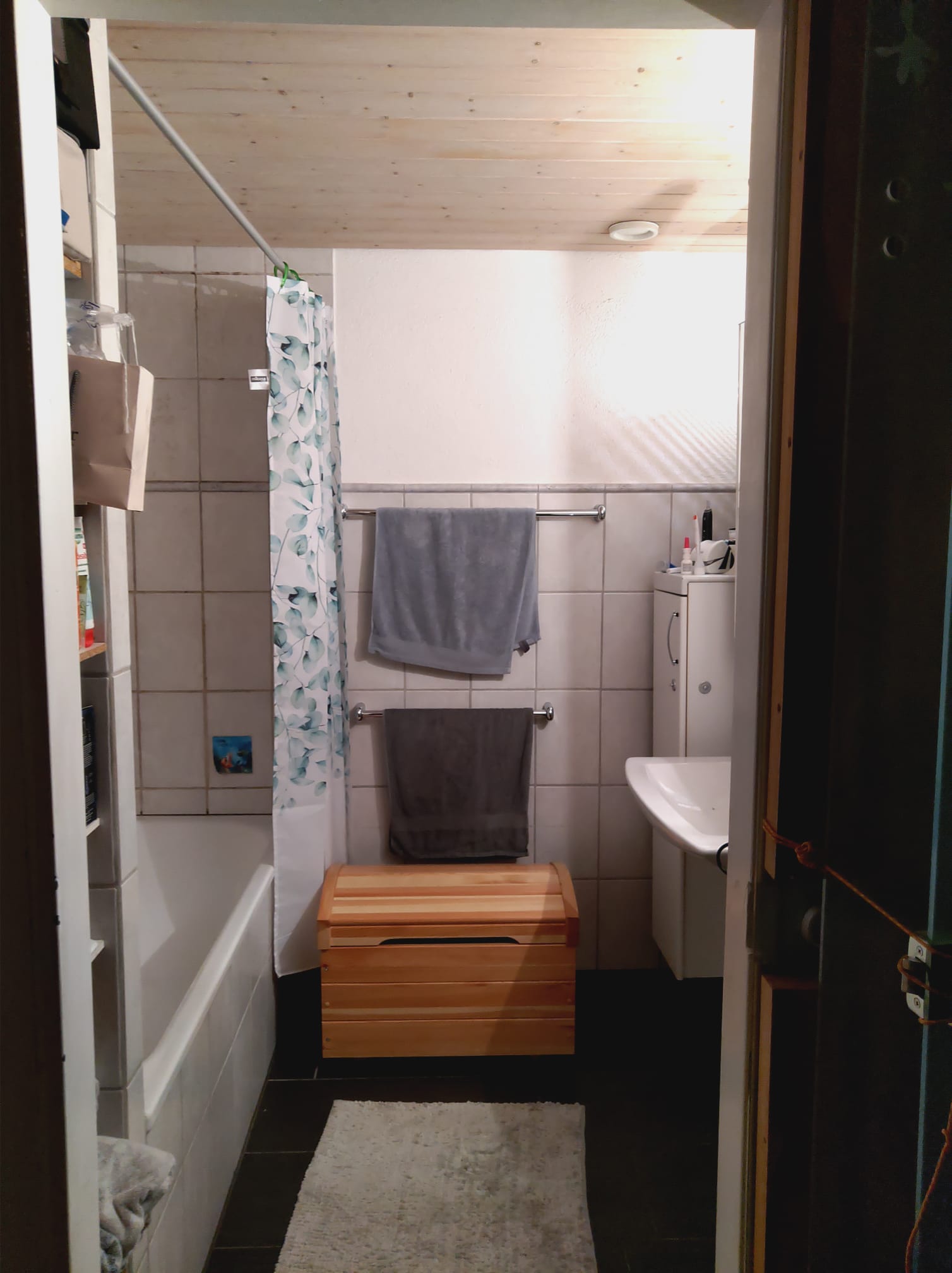 Badezimmer mit Wanne und Holzhocker